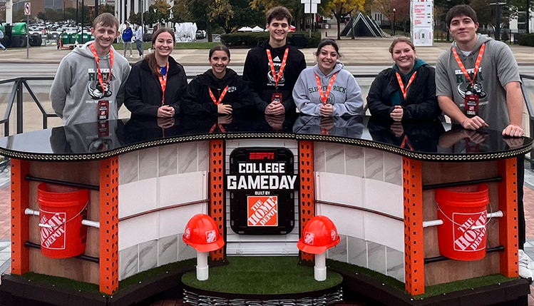 Students standing behind ESPN College Game Day desk