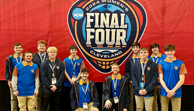 Students standing in front of the National Collegiate Athletics Association's 2024 Women's Final Four Basketball Banner