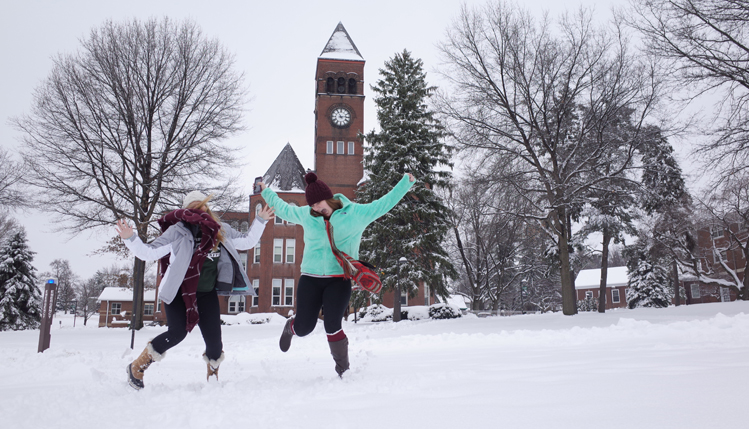 Students jumping with joy in front of old main