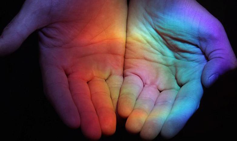 colored lights reflecting on pair of hands