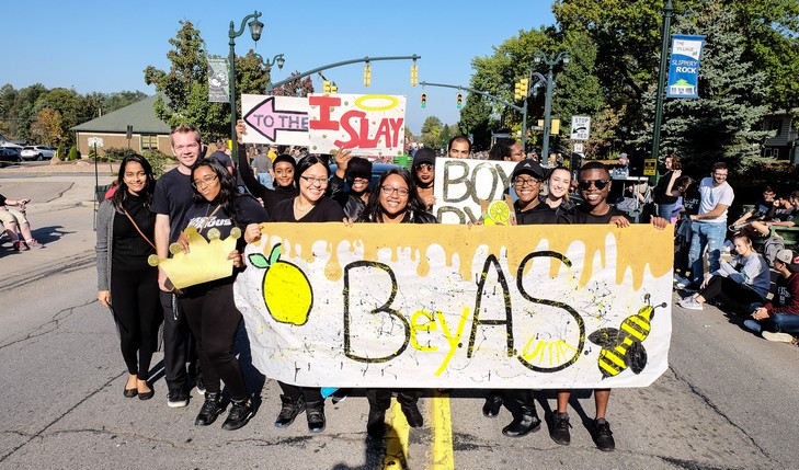 Group holding sign with a bee on it