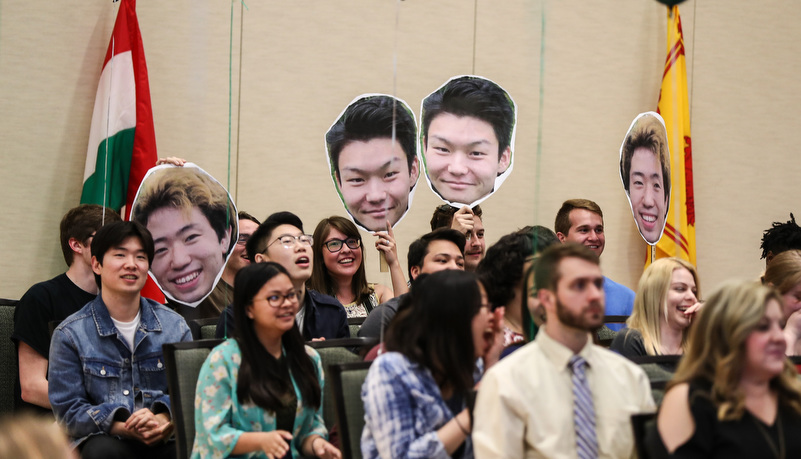 students hold up cutouts of their friends as they graduate