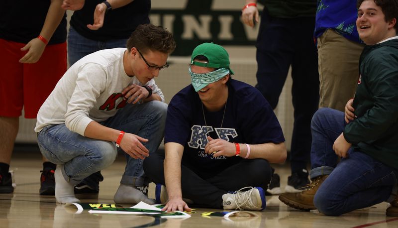 Blindfolded Kappa Sigma students using touch to piece back together torn papers