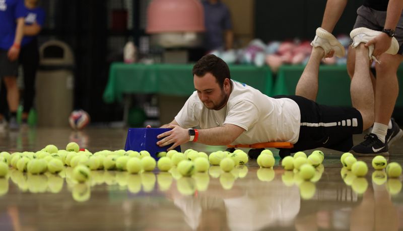 Guy scooping tennis balls in a game