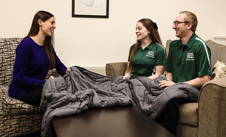 Students and a professor discuss the benefits of a weighted blanket