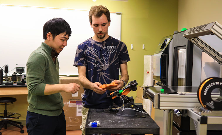Professor and student working with a robotic arm