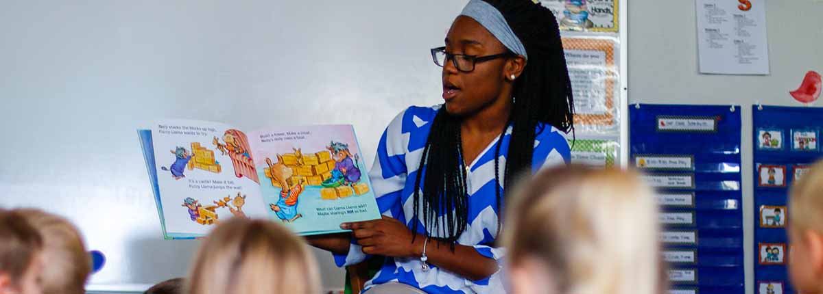 Student reading a book to children