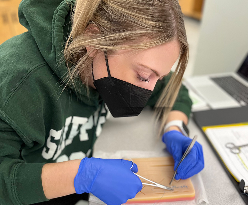 A student with a black mask ans surgical scissors