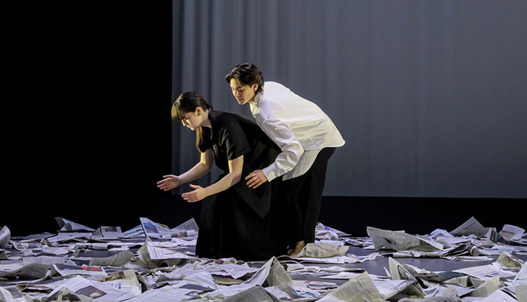students perform on top of newspapers.