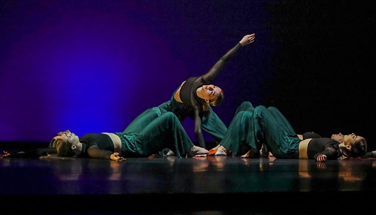 Dancers in red costumes on stage with black background