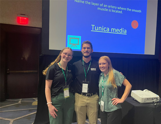 Three people in front of a projector.