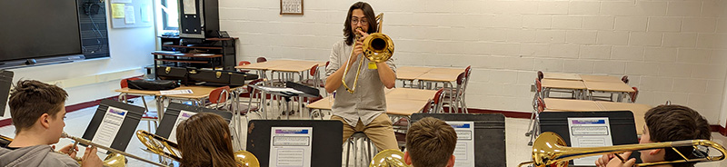 A student teaching how to play the Trombone
