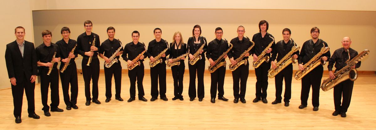 Students in a curved line on stage holding their saxophones