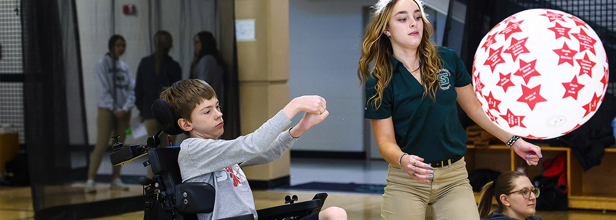 Adaptive sports day photo of a young man hitting a ball.
