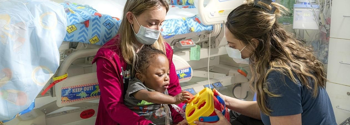 Baby playing toys with a recreational therapist in a hospital.