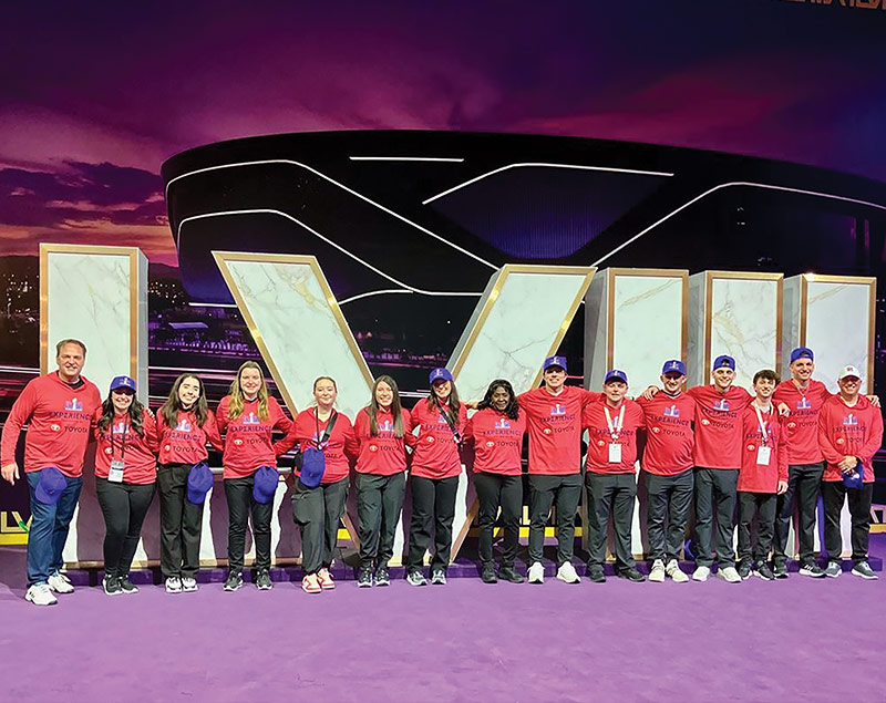 Many students and staff in front of superbowl sign