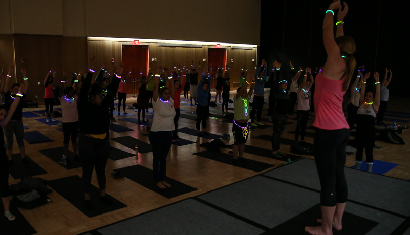 Students wearing glow sticks while doing yoga