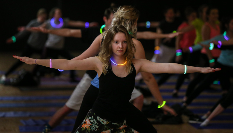 A woman doing yoga and wearing glow sticks