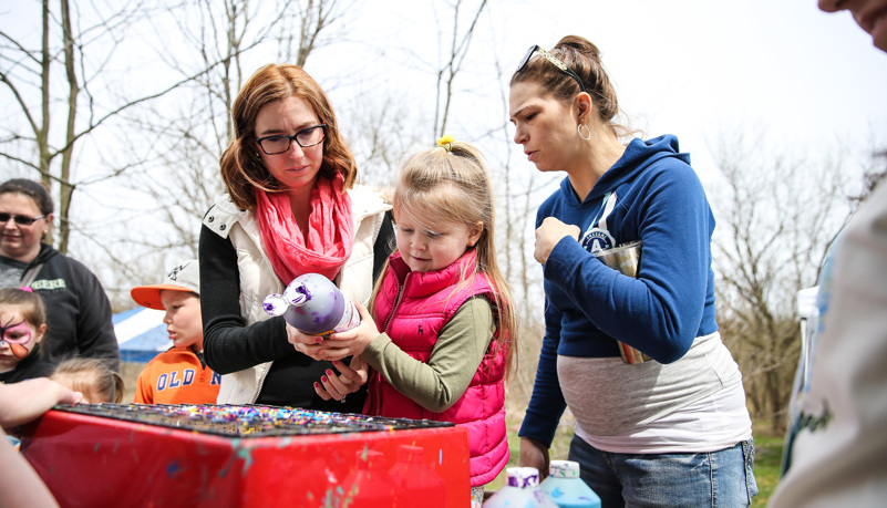 A mother helps her daughter with paint