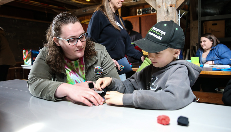 Student helps a boy with a craft