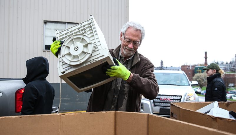 Man putting a comupter into a recycling box
