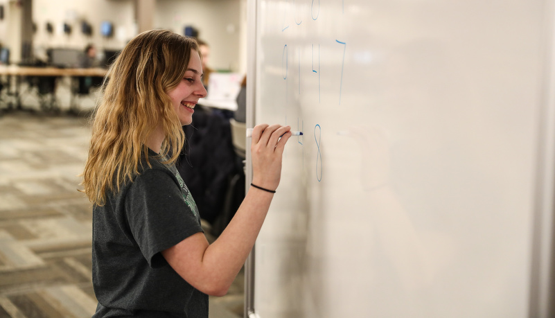 Woman writing on a dry erase board