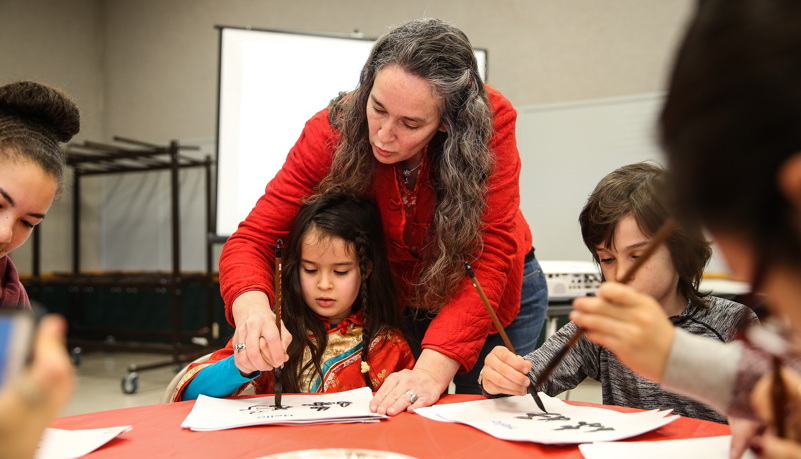 Woman helping girl paint