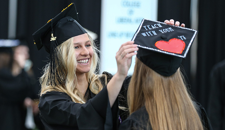 Graduate helping  another graduate with her cap