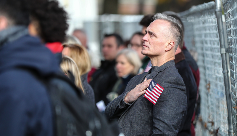 Man with his hand over his heart with an American flag 