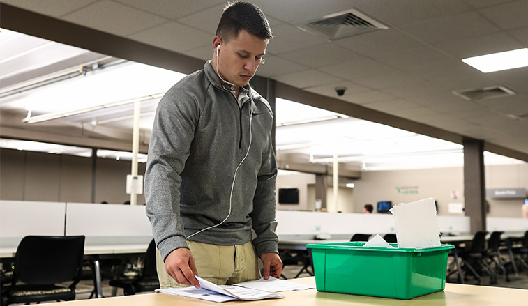 A student sorts through papers that hee has print for his classwork