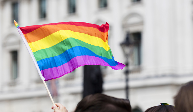 Pride flag flying over a crowd