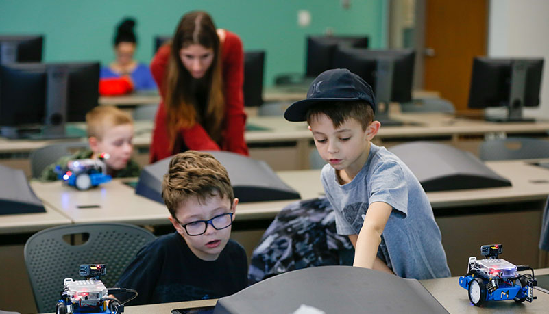 child helping another child with robot