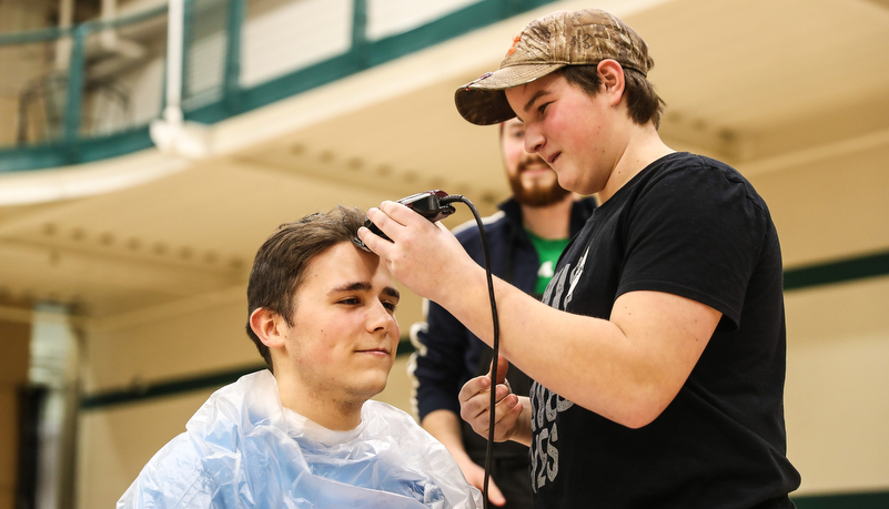 Student getting his head shaved after raising money to do so