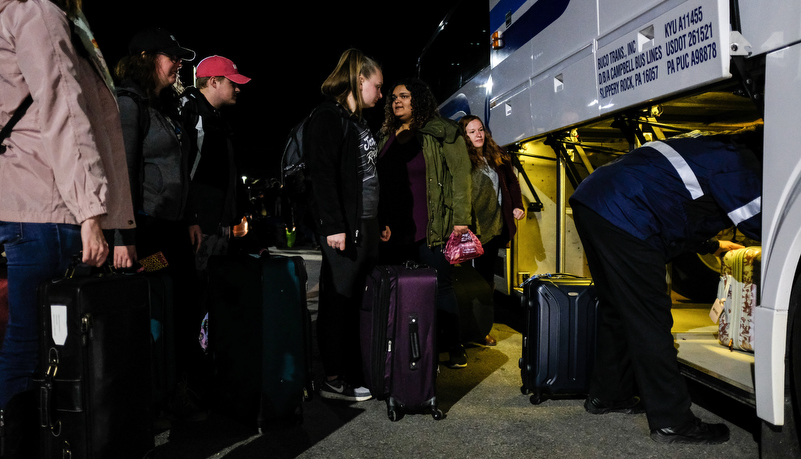 Students loading bags into the bus