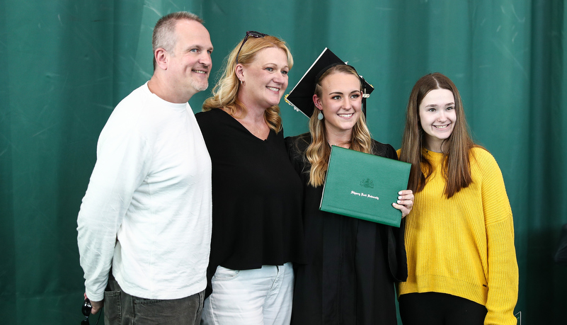 student poses for a photo with family