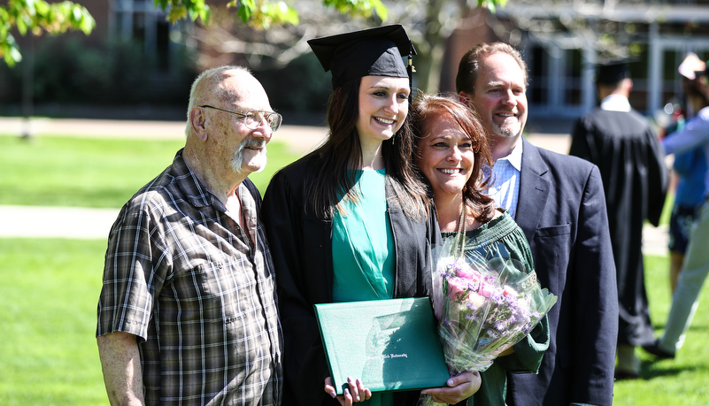 student poses for a photo with family