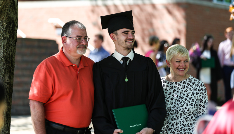 student poses for a photo with family