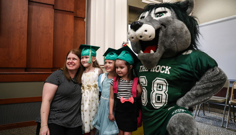 Pre-schoolers and their teacher pose with Rocky