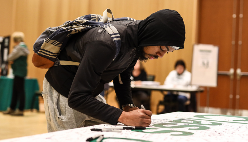 graduate candidate signing a banner