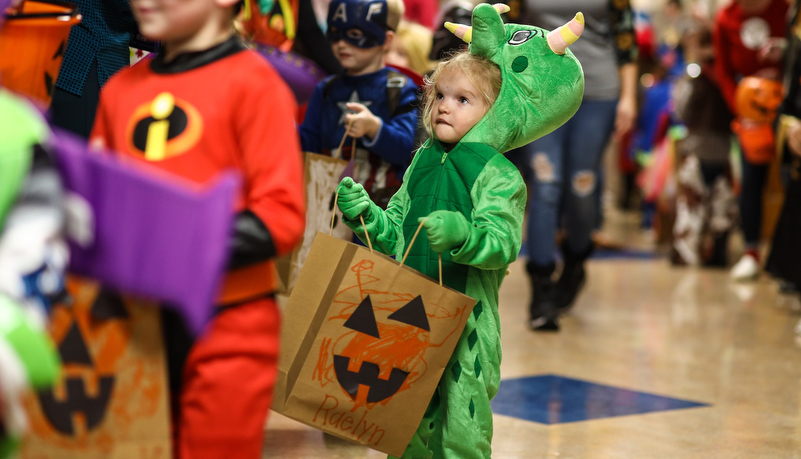 pre-school girl dressed as a dinosaur trick or treating on campus