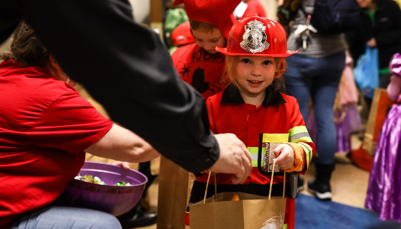 pre-school girl dressed as a fire fighter trick or treating on campus