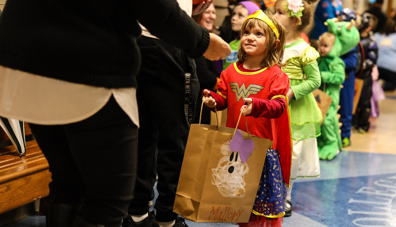 pre-school girl dressed as wonder woman trick or treating on campus