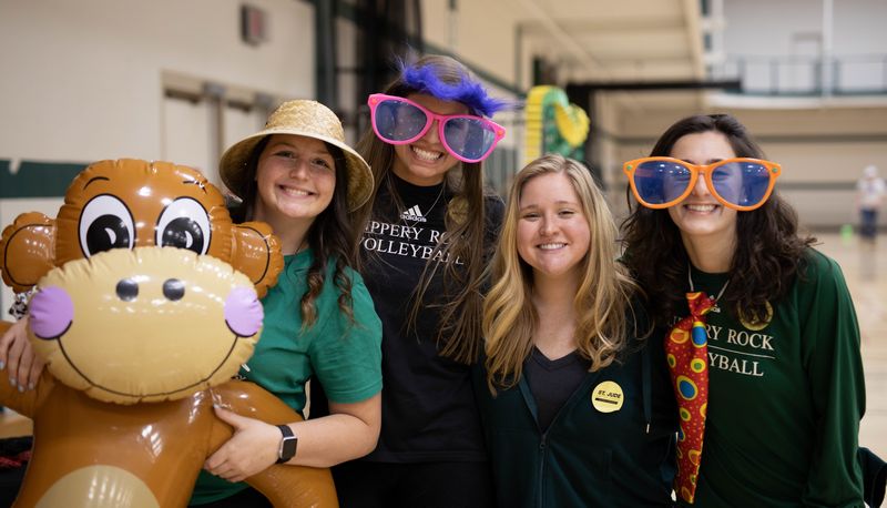 Students posing with silly props and inflatable monkey