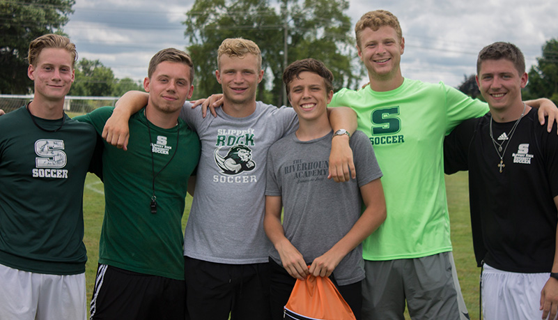 Men jubilantly standing with each other smiling at the camera wearing SRU apparel.