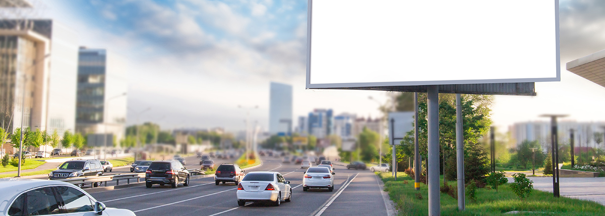 Image of a blank billboard on a busy highway with a city in the background