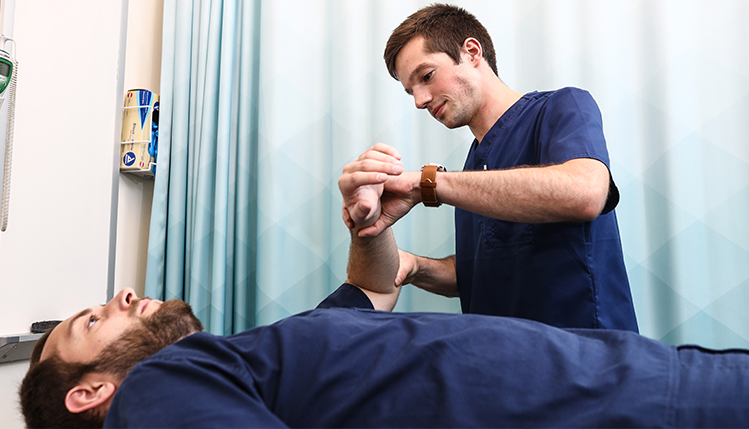 Two PA students practicing an arm examination