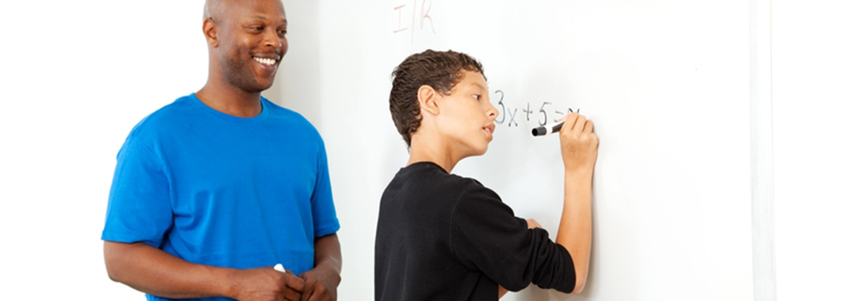 Professor helping student with equation on whiteboard