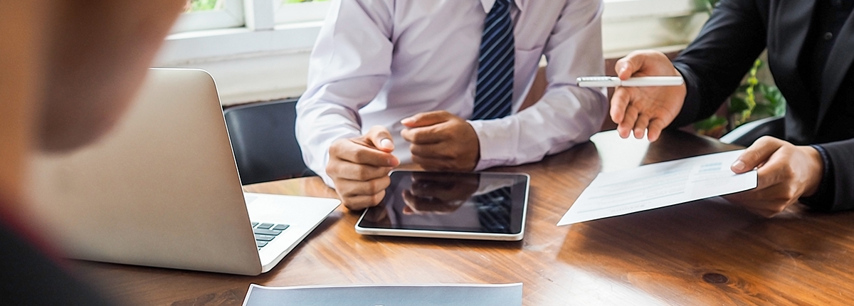 two business people at a table with papers and an ipad