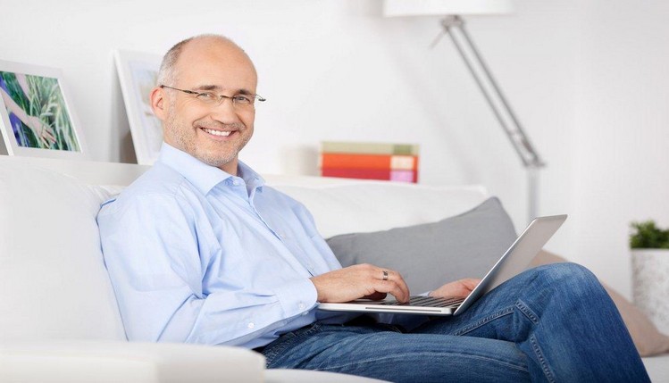 smiling man sitting with laptop