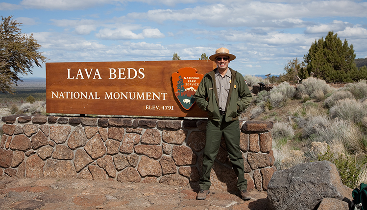 Park ranger in front of sign